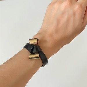 Gold color bow and black faux leather bracelet